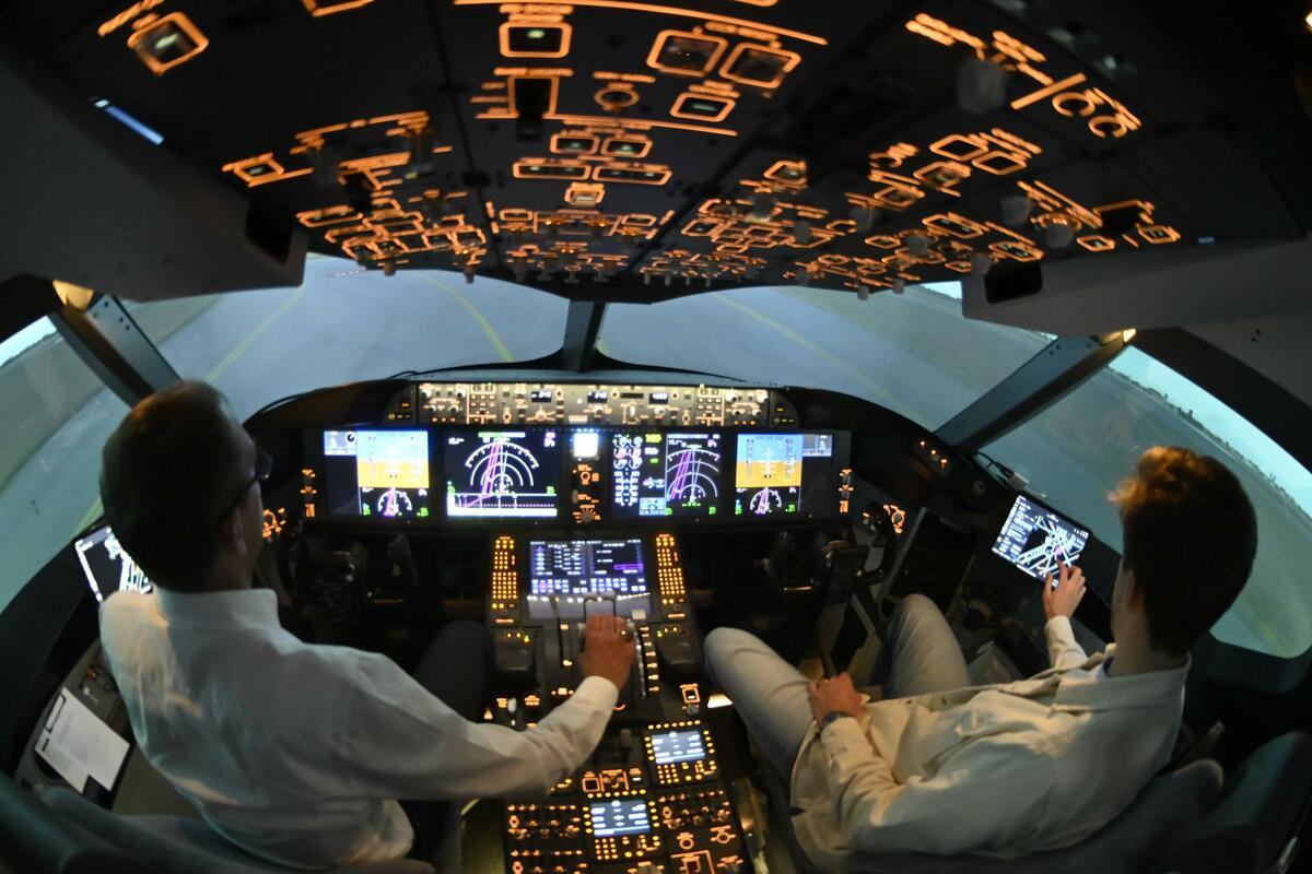 Two people sitting in a Boeing cockpit simulator in Frankfurt.